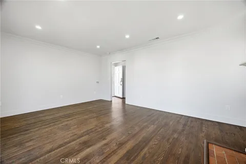 a view of an empty room with wooden floor and closet