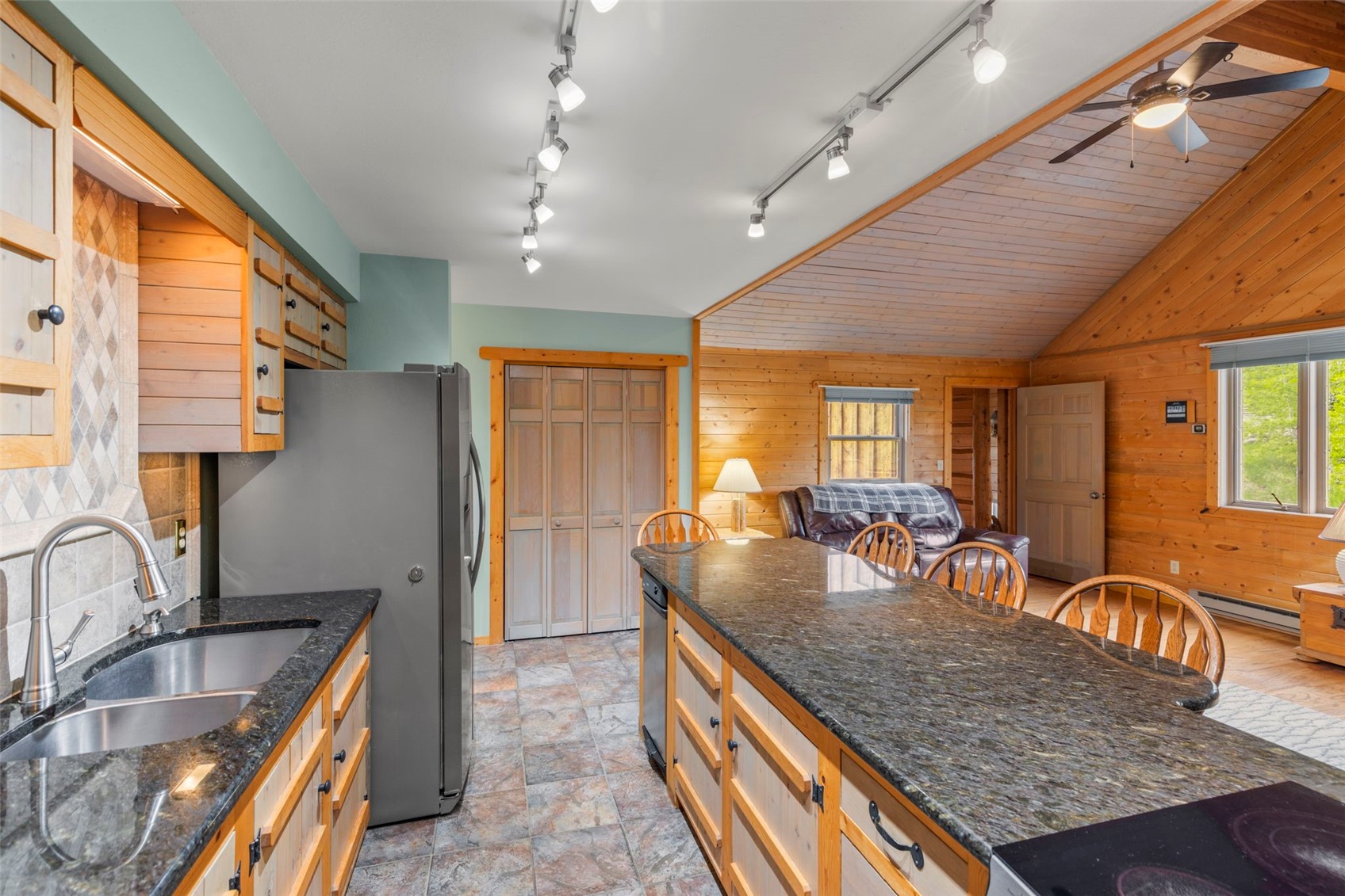 1516 Blue Ridge Road Silverthorne, CO 80498 - Photo 16 of 50 Kitchen with wood walls, freestanding refrigerator, a ceiling fan, lofted ceiling, and dark stone counters