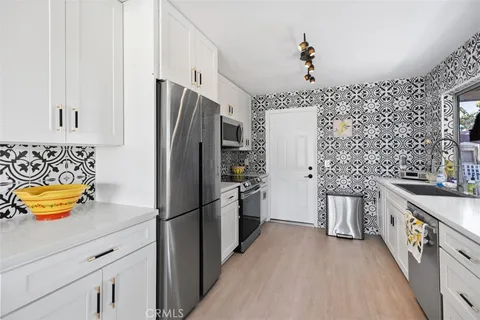 a kitchen with stainless steel appliances granite countertop a refrigerator a stove and a sink