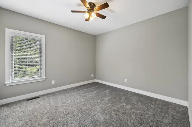 an empty room with a window and a fan