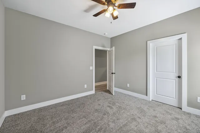 a view of an empty room with a chandelier fan