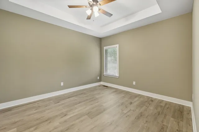 a view of an empty room with window and chandelier fan