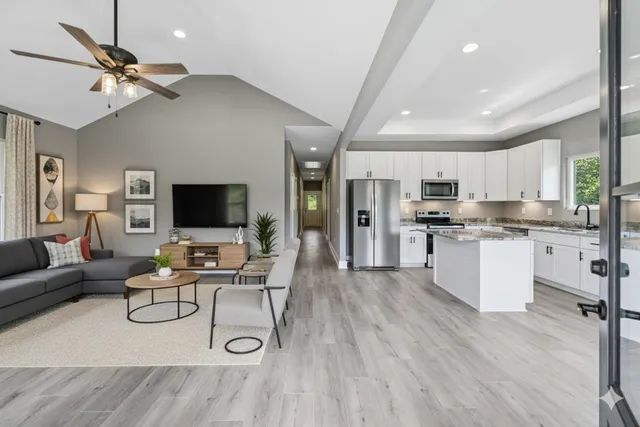 a living room with stainless steel appliances furniture and a flat screen tv