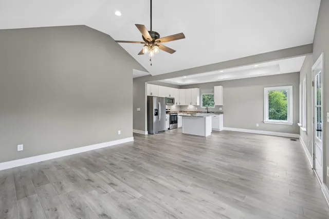 an empty room with wooden floor fan and windows
