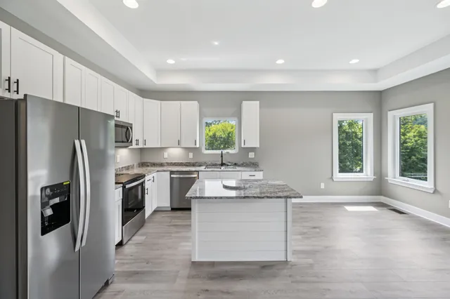 a kitchen with stainless steel appliances granite countertop a refrigerator sink and stove