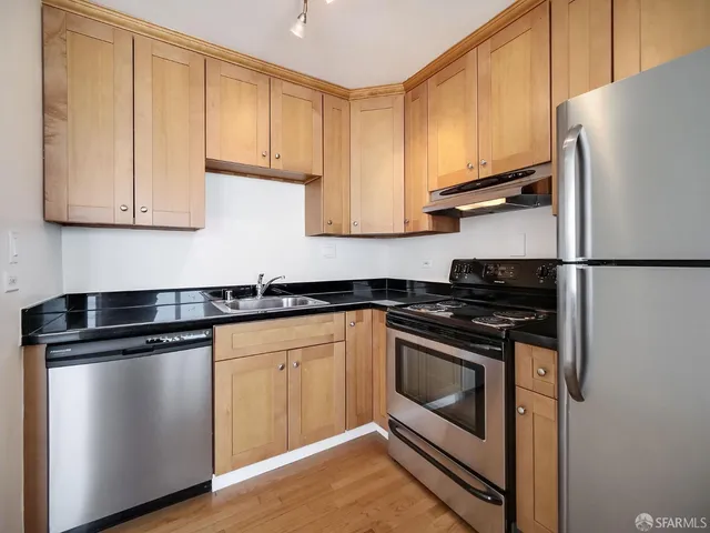 a kitchen with stainless steel appliances granite countertop a stove a sink and a refrigerator
