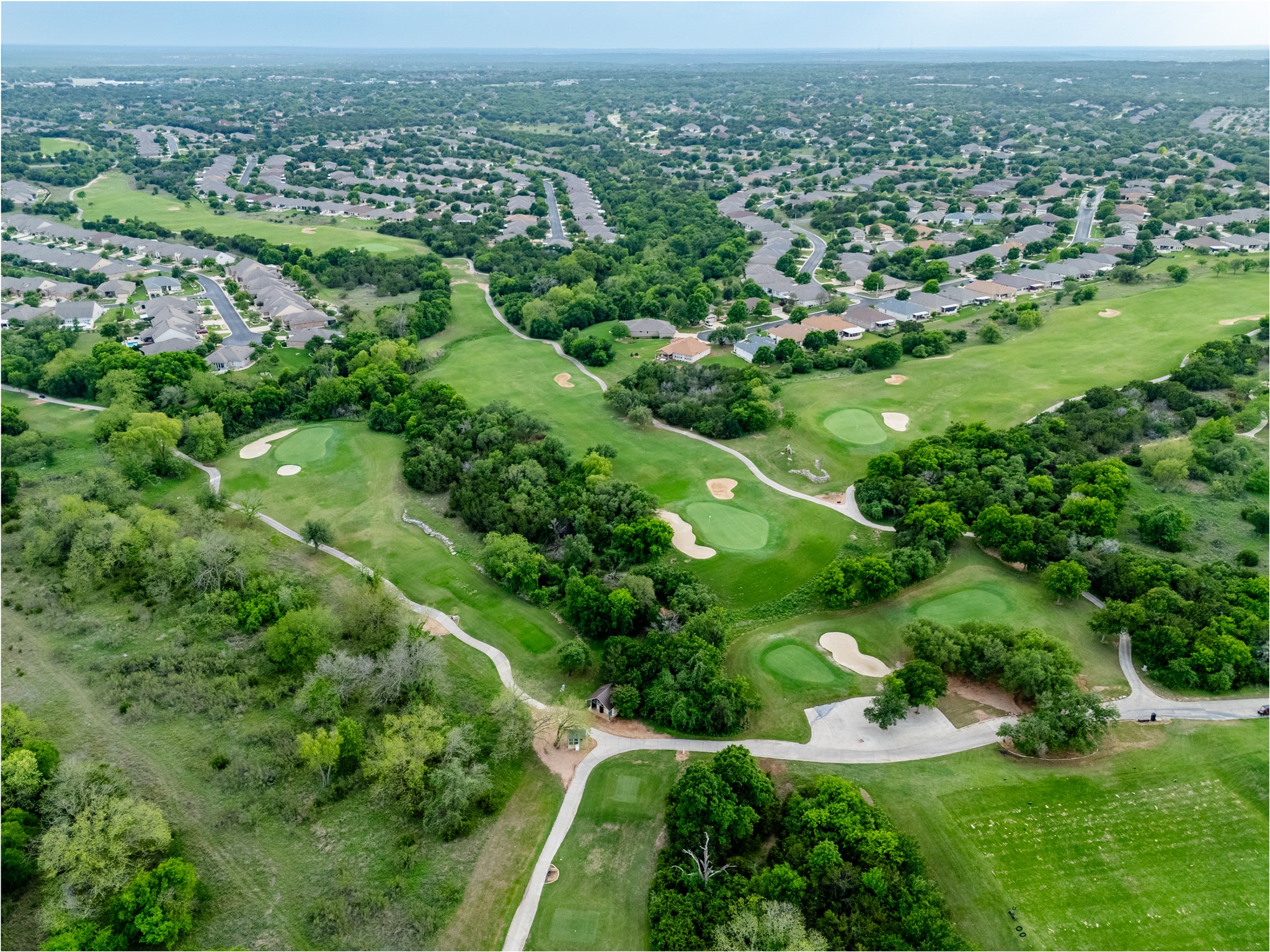 214 Summit Street Georgetown, TX 78633 - Photo 36 of 38 This aerial view showcases a verdant golf course with multiple greens and sand traps, surrounded by mature trees
