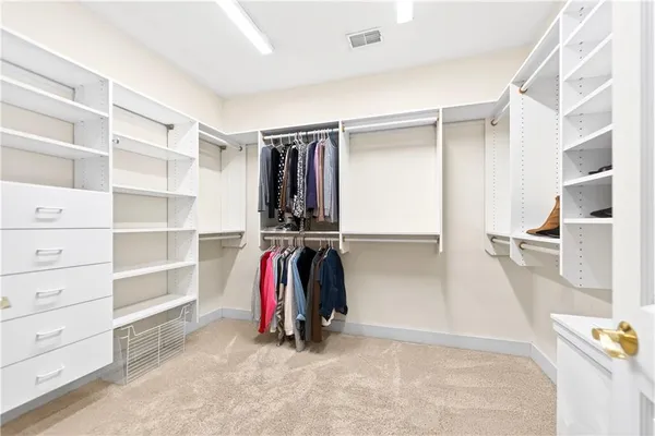 a view of walk in closet with clothes and shoes