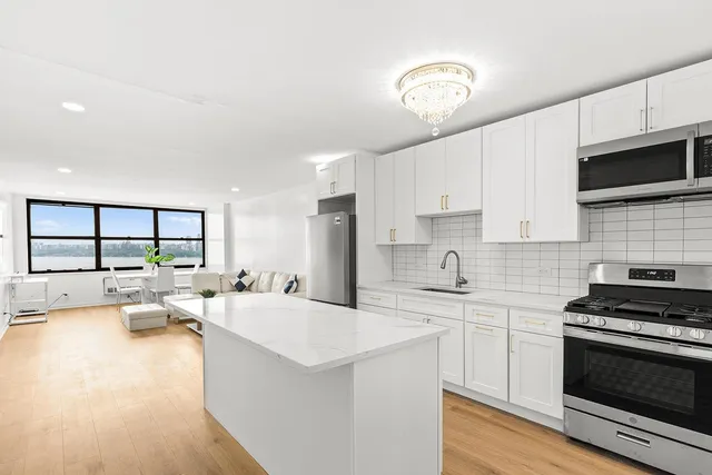 a kitchen with stainless steel appliances a refrigerator a stove a sink and white cabinets