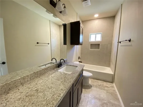 a bathroom with a granite countertop sink toilet and shower