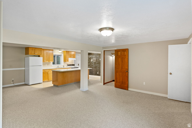 435 Canyon Road Millville, UT 84326 - Photo 38 of 113 Open-concept living space featuring light-toned carpeting and a kitchen area with wood cabinetry, white appliances, and a peninsula