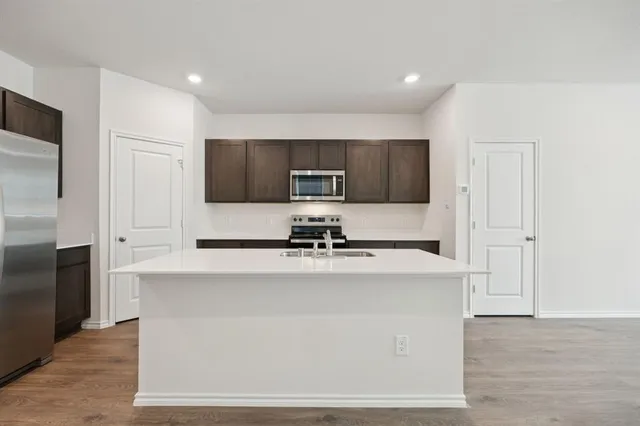 a kitchen with a sink a stove a refrigerator a center island and a window