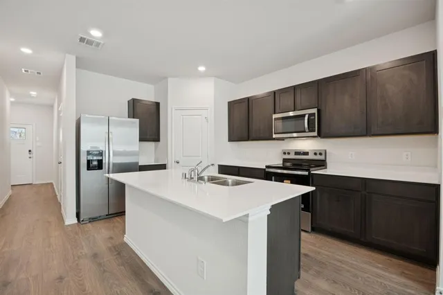 a kitchen with stainless steel appliances a sink a stove a refrigerator a microwave and cabinets