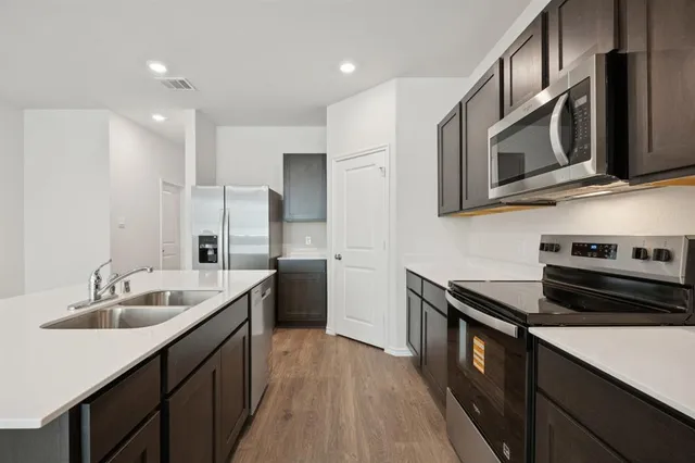 a kitchen with a sink a counter top space stainless steel appliances and cabinets