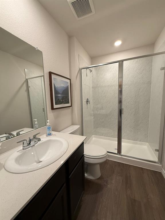 323 Clematis Street Princeton, TX 75407 - Photo 27 of 34 Bathroom featuring dark wood-style flooring, vanity, a shower stall, and a textured wall