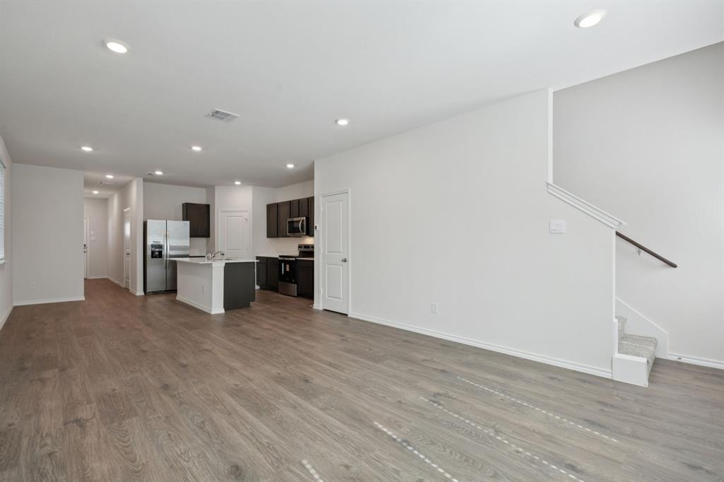 323 Clematis Street Princeton, TX 75407 - Photo 4 of 34 Unfurnished living room with recessed lighting, dark wood-style floors, and stairway