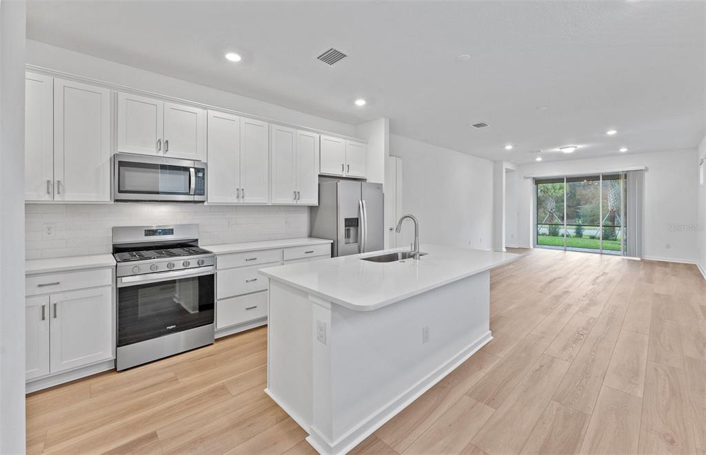 13748 Rocky Pne Place Spring Hill, FL 34610 - Photo 5 of 30 a kitchen with stainless steel appliances granite countertop a sink stove and refrigerator