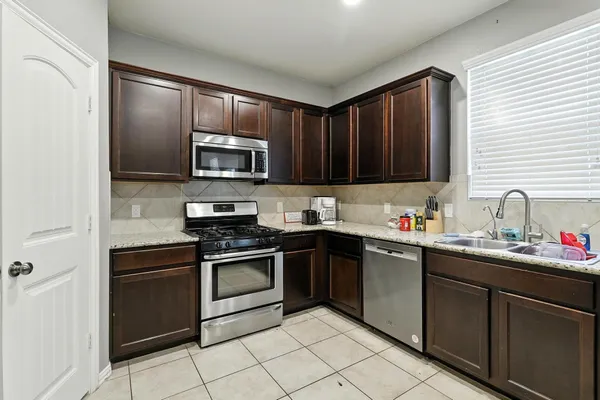 a kitchen with granite countertop wooden cabinets and stainless steel appliances