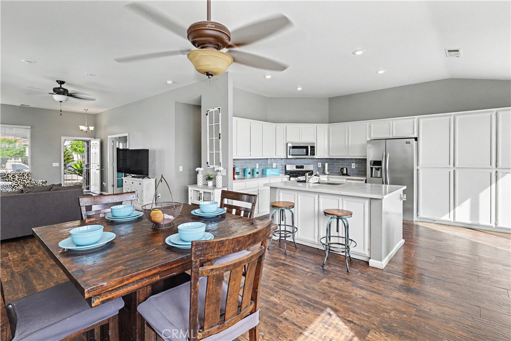 3632 Swan Court Merced, CA 95340 - Photo 18 of 50 a kitchen with a dining table chairs refrigerator and microwave