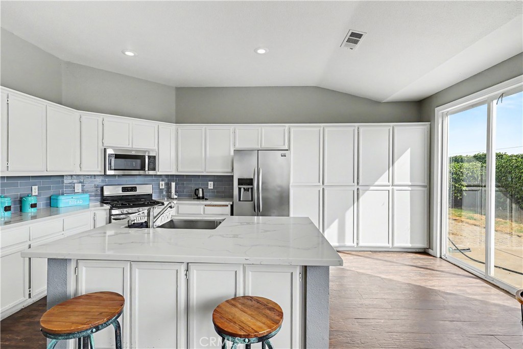 3632 Swan Court Merced, CA 95340 - Photo 21 of 50 a kitchen with stainless steel appliances granite countertop a refrigerator a stove a sink dishwasher and white cabinets with wooden floor