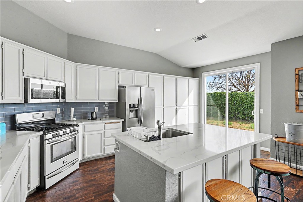 3632 Swan Court Merced, CA 95340 - Photo 22 of 50 a kitchen with stainless steel appliances a stove a sink dishwasher a refrigerator white cabinets and wooden floor