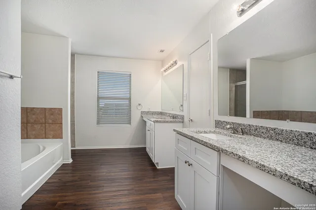 a bathroom with a granite countertop sink mirror and bathtub
