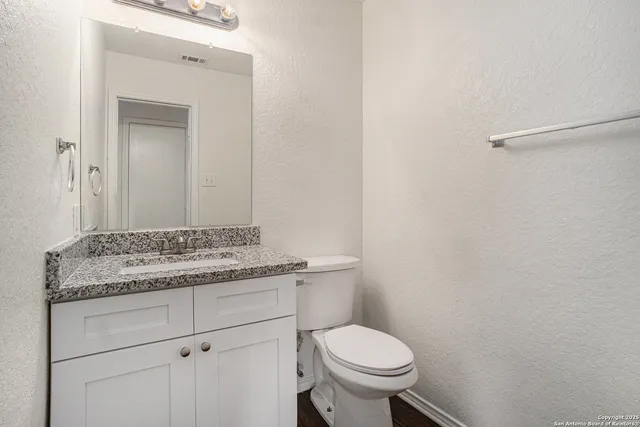 a bathroom with a granite countertop toilet and sink