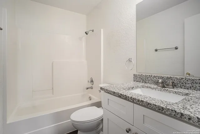 a bathroom with a granite countertop sink a toilet and shower