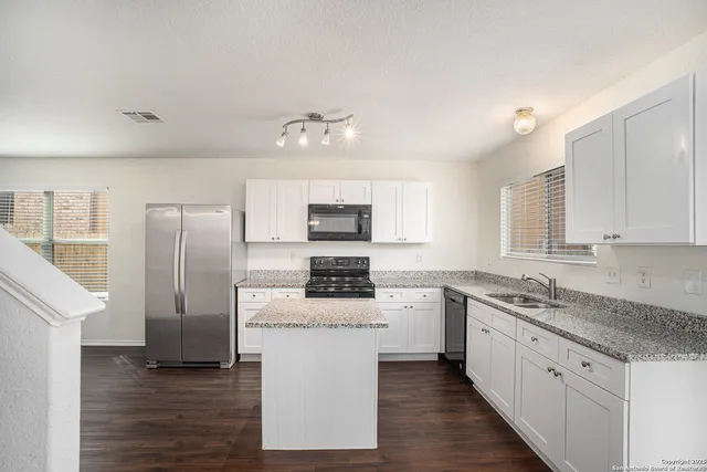 a kitchen with stainless steel appliances granite countertop a stove top oven a refrigerator a sink and dishwasher