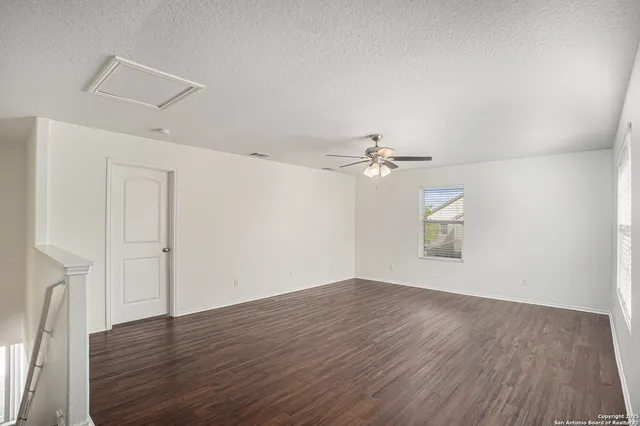 an empty room with wooden floor ceiling fan and window