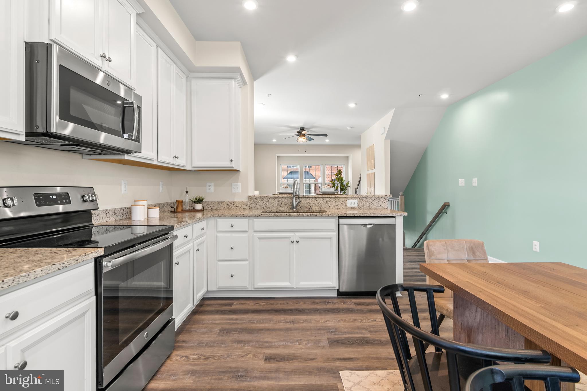 4701 Marlene Mews Baltimore, MD 21224 - Photo 11 of 39 a kitchen with stainless steel appliances granite countertop a stove top oven a sink dishwasher a dining table and chairs with wooden floor
