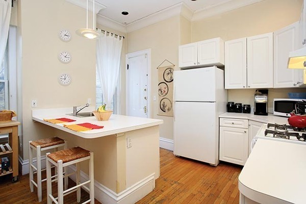 17 High Street, Unit 2 Brookline, MA 02445 - Photo 3 of 6 a kitchen with a refrigerator a stove a sink and white cabinets with wooden floor