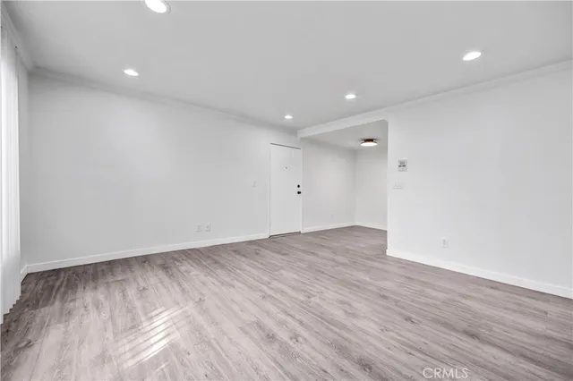 an empty room with wooden floor and natural light