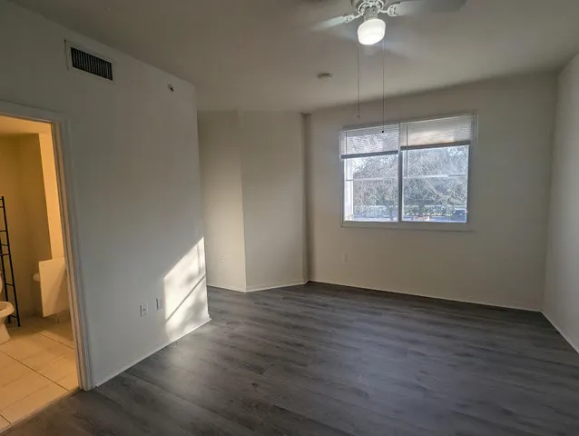a view of empty room with wooden floor and fan