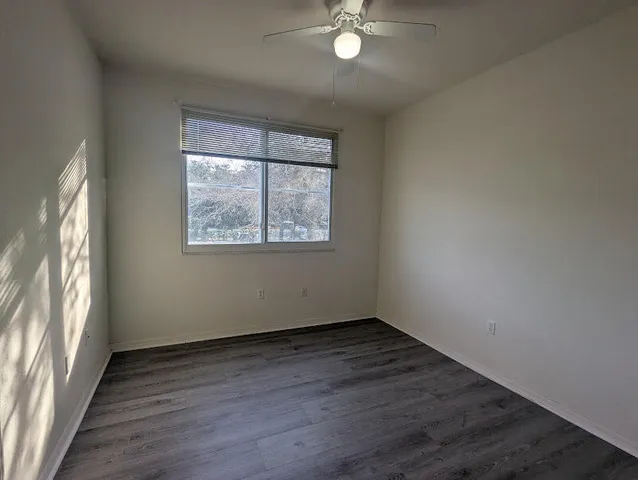 an empty room with wooden floor and fan
