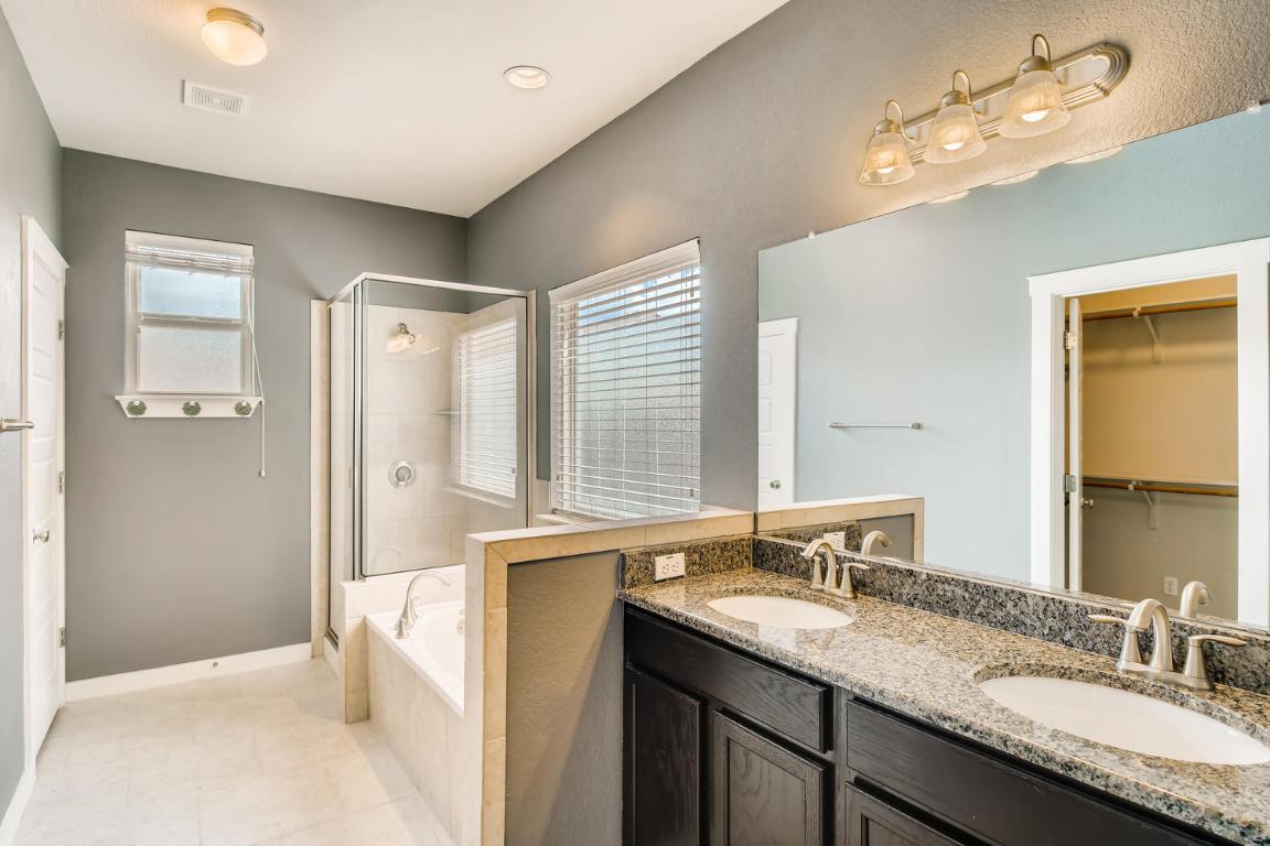 16229 Travesia Way Austin, TX 78728 - Photo 17 of 28 a bathroom with a granite countertop sink a large mirror and a shower