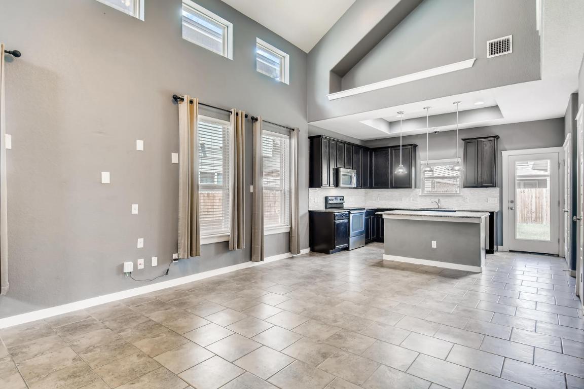 16229 Travesia Way Austin, TX 78728 - Photo 7 of 28 a large white kitchen with kitchen island granite countertop a large counter top stainless steel appliances and cabinets