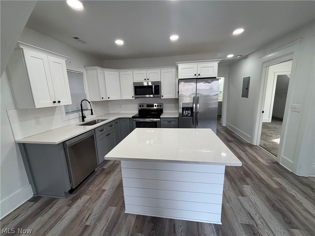 4115 Whitman Avenue, Unit UP Cleveland, OH 44113 - Photo 2 of 12 Kitchen with stainless steel appliances, dual tone cabinetry, dark wood-type flooring, light stone countertops, and a center island