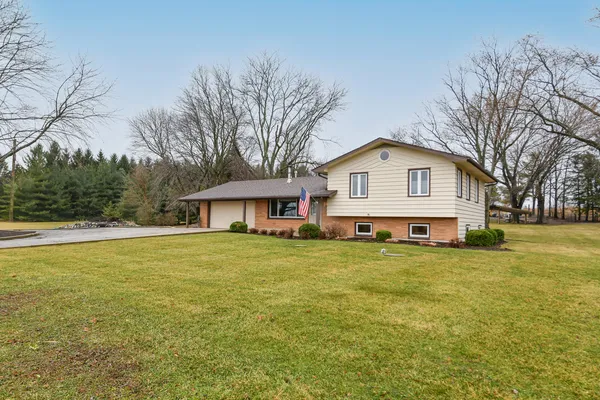 a front view of a house with a garden and trees