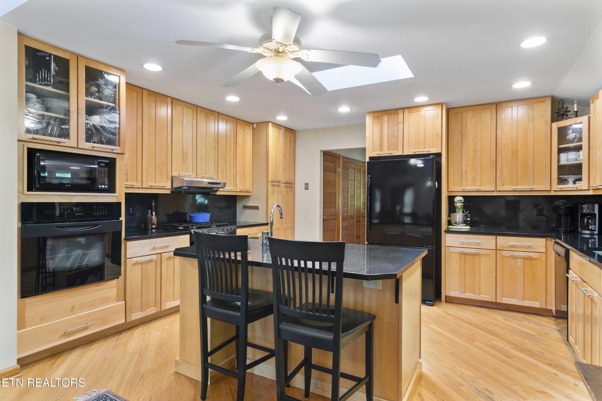 780 Old Emory Road Clinton, TN 37716 - Photo 15 of 33 a kitchen with stainless steel appliances kitchen island granite countertop a refrigerator a stove top oven and a dining table with wooden floor