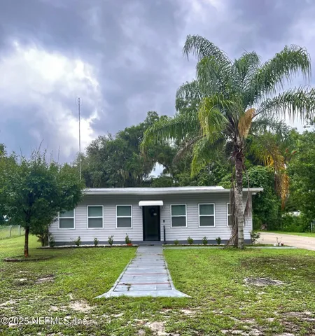 a front view of a house with a garden and trees