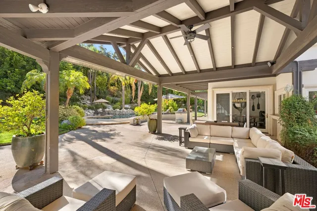 a view of a patio with table and chairs potted plants with wooden floor and floor to ceiling window