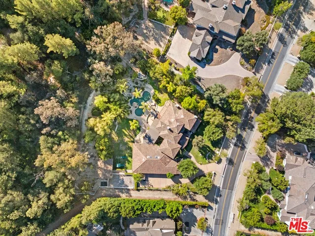 an aerial view of residential house with outdoor space and trees all around