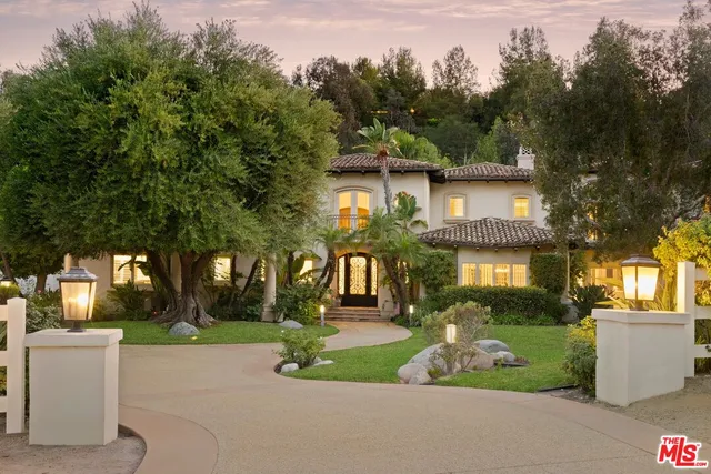 a front view of a house with a garden and tree