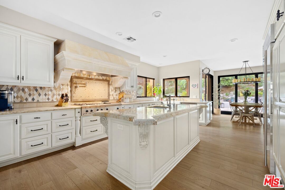 25217 Eldorado Meadow Road Hidden Hills, CA 91302 - Photo 8 of 28 a large white open kitchen with stainless steel appliances kitchen island a large counter space a sink and living room view