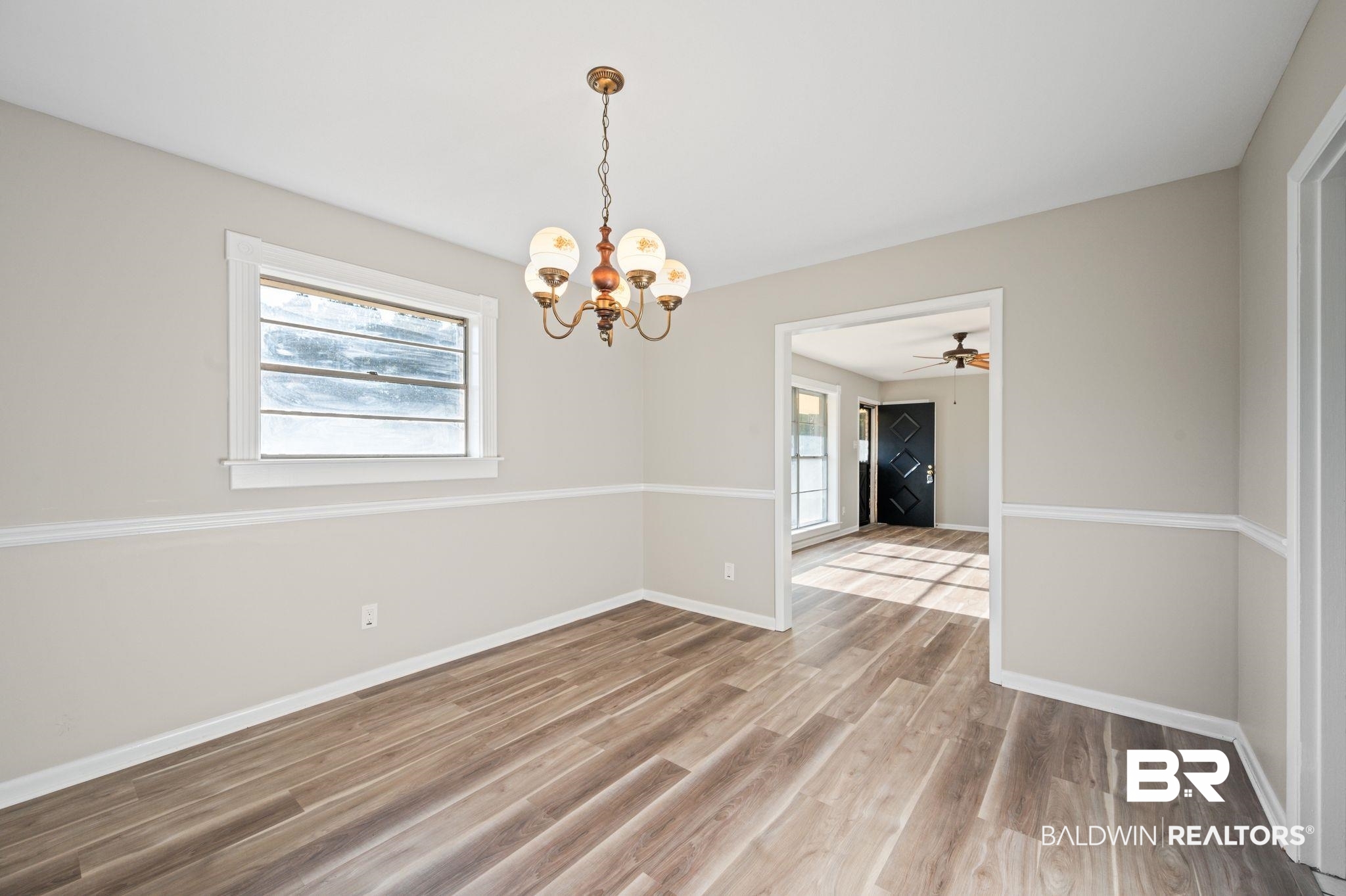 909 Caroline Avenue Daphne, AL 36526 - Photo 14 of 46 Unfurnished room with ceiling fan with notable chandelier, hardwood / wood-style flooring, and a healthy amount of sunlight