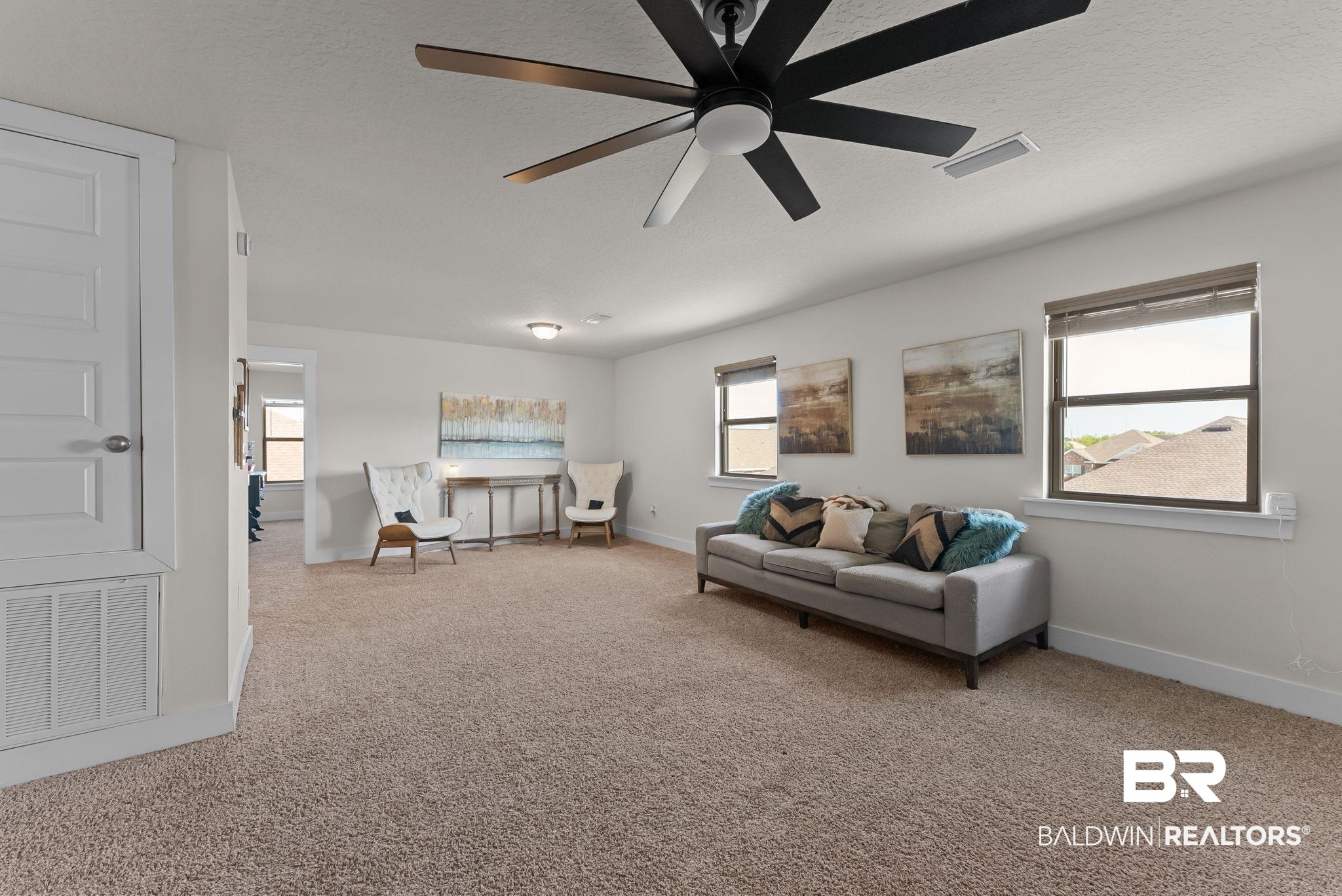 16607 Prado Loop Loxley, AL 36551 - Photo 19 of 46 Spacious loft area featuring neutral-toned carpeting, multiple windows, a modern ceiling fan, and recessed lighting