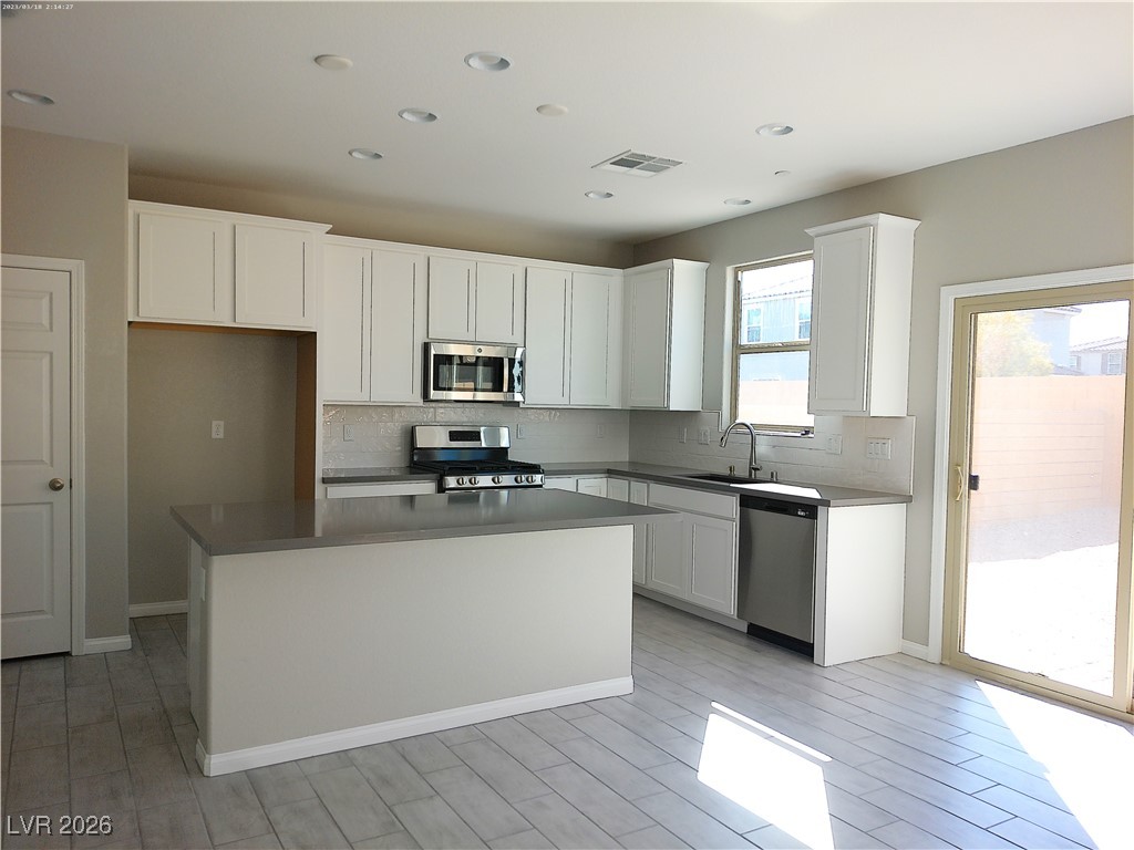 6607 Dove Point Place Las Vegas, NV 89130 - Photo 2 of 14 Kitchen with decorative backsplash, stainless steel appliances, white cabinetry, a center island, and recessed lighting