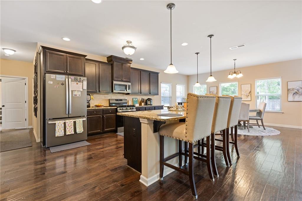 2352 Alexander Top Place Grayson, GA 30017 - Photo 18 of 66 a kitchen with stainless steel appliances granite countertop a refrigerator a stove top oven a sink dishwasher a dining table and chairs with wooden floor