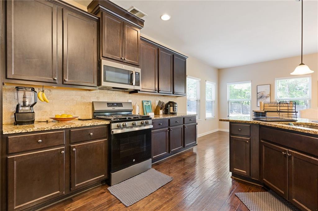 2352 Alexander Top Place Grayson, GA 30017 - Photo 21 of 66 a kitchen with stainless steel appliances granite countertop wooden cabinets a stove top oven a sink and dishwasher